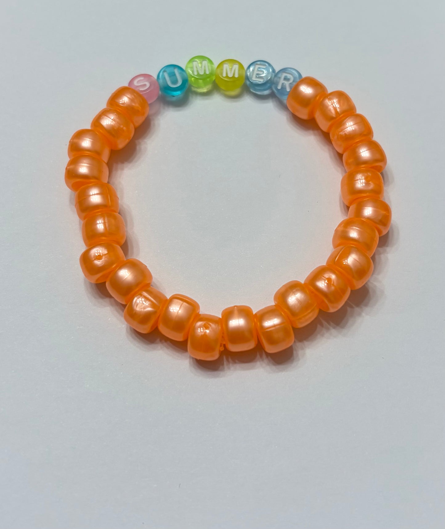 Shiny orange pony beads with the word summer in the middle