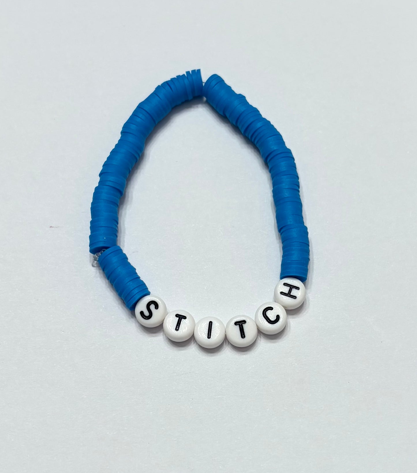 Blue clay beaded bracelet with the word stitch in the middle